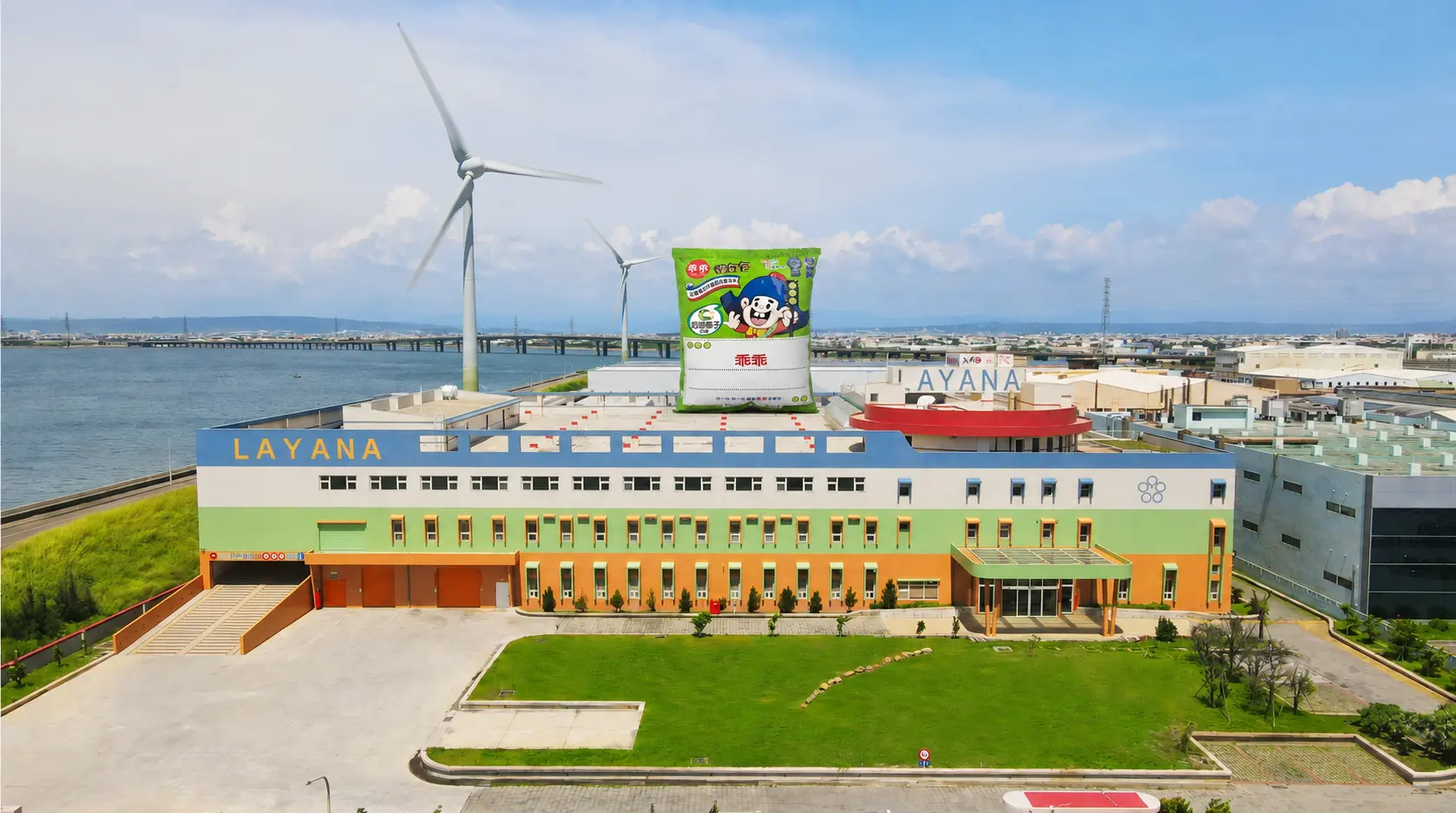 Vista aérea compuesta por IA de la fábrica de Lukang de Layana con una bolsa de refrigerios verde gigante Kuai Kuai en el estacionamiento de la azotea del cuarto piso